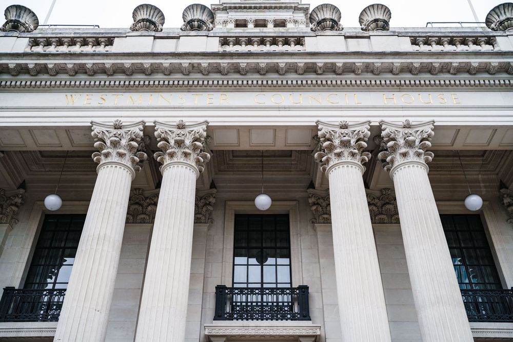 Classical building facade with ornate Corinthian columns and round dormers along the roofline.