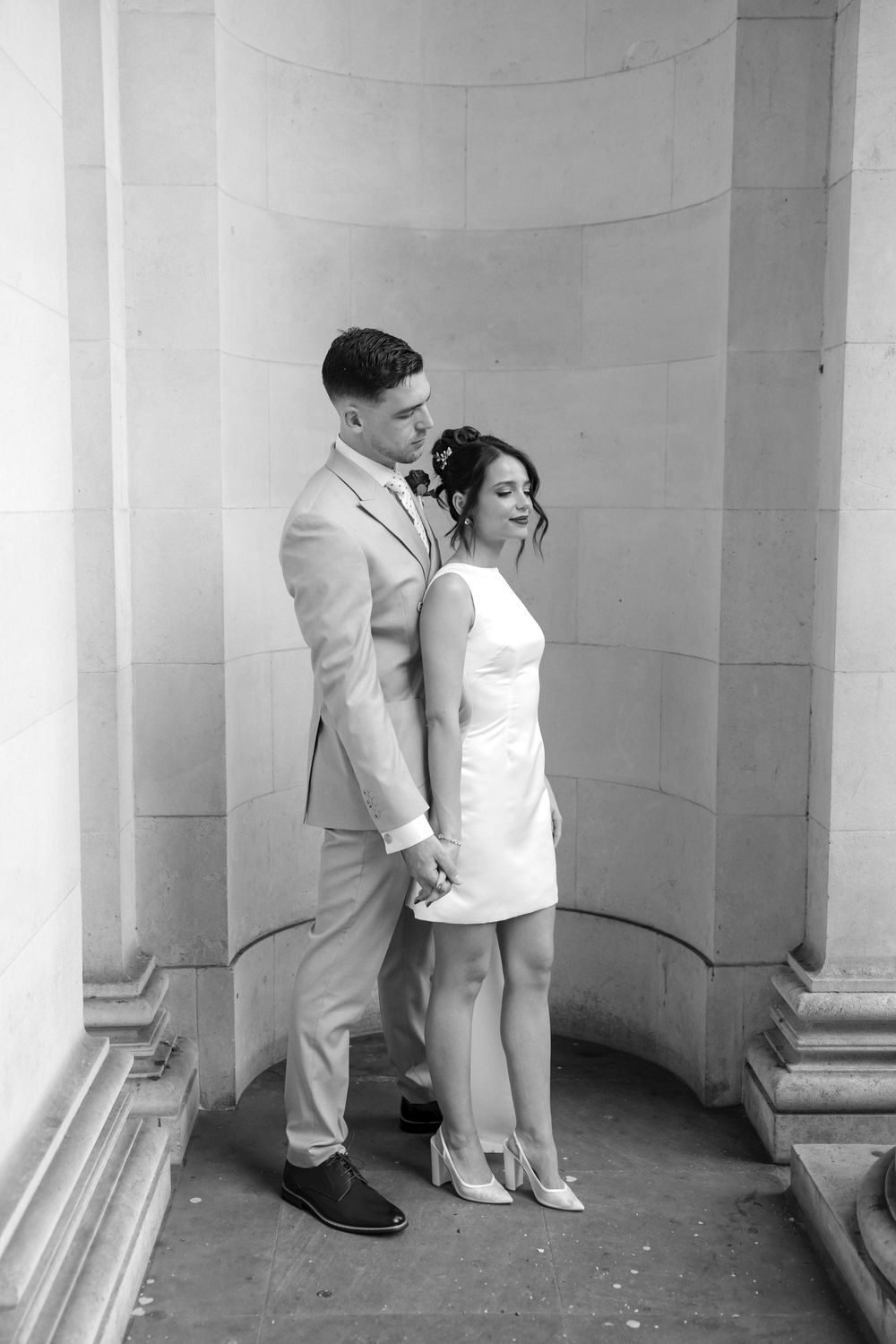 A series of four connected black and white photos show two people in formal wear posing together in architectural alcoves.