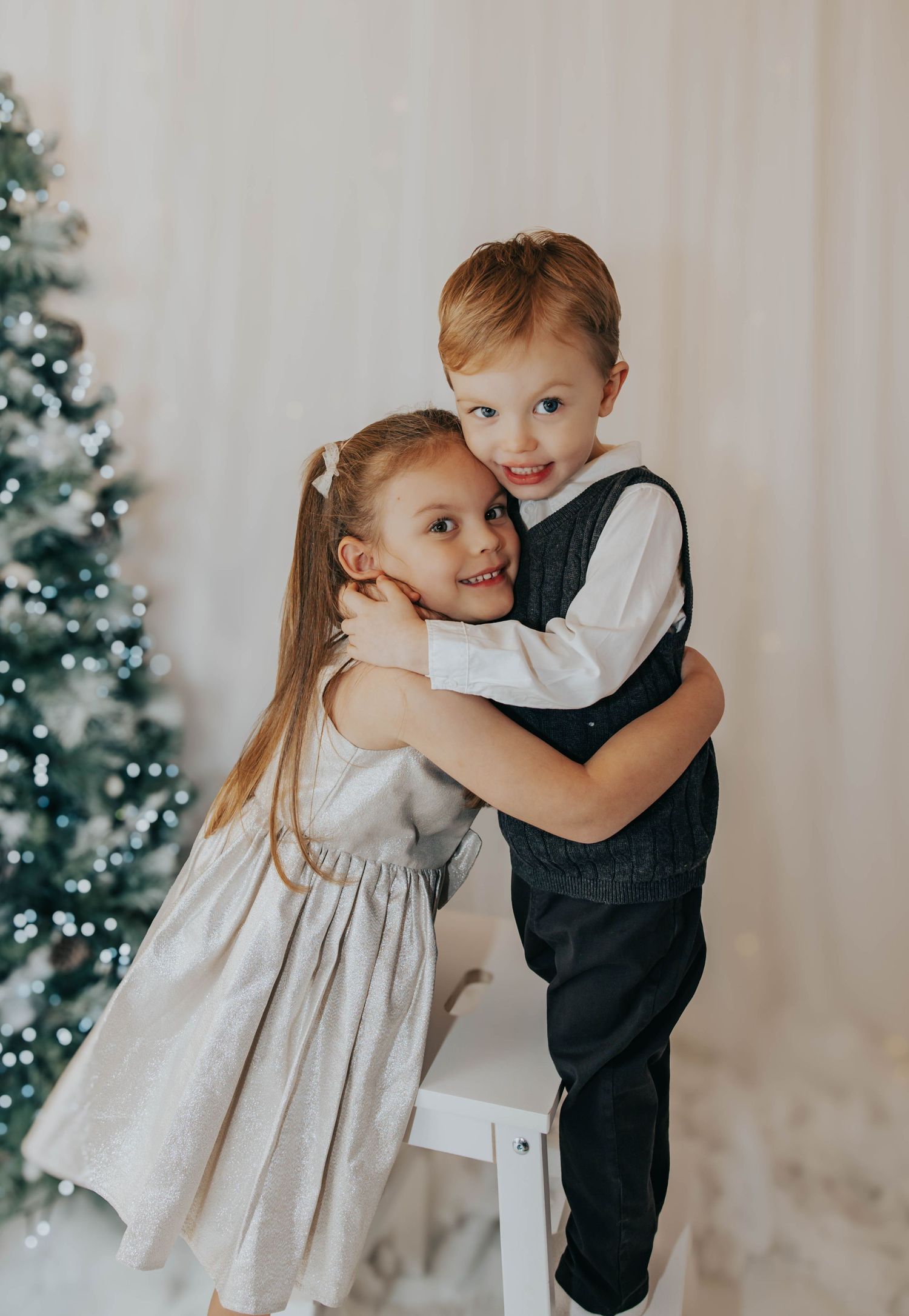 Children in formal attire share sweet moment during holiday photoshoot.