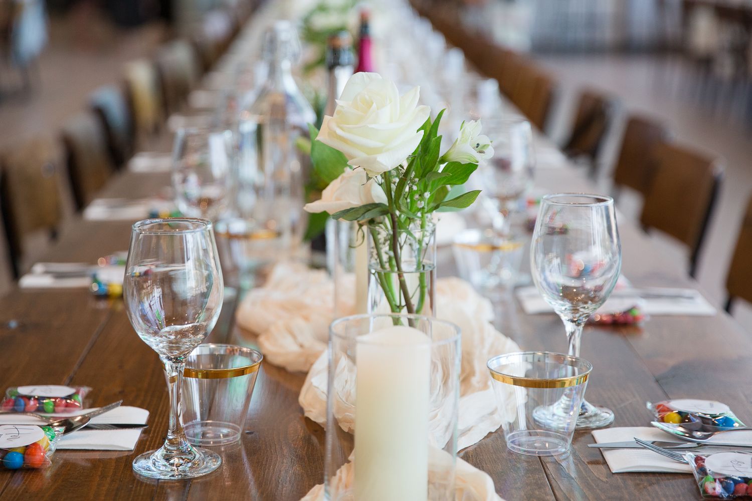 An elegant wedding table setting with wine glasses, candles and simple white floral centerpieces.