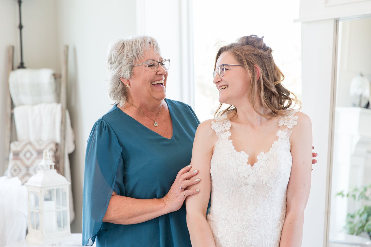 Two people share joyful moment together in white formal attire indoors.