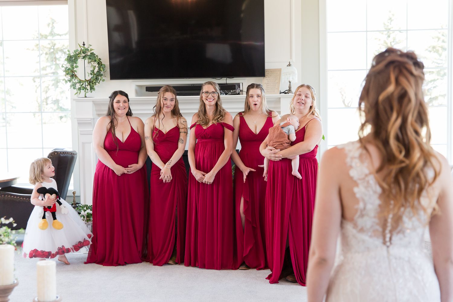 Bridesmaids in burgundy dresses stand together during a wedding ceremony.