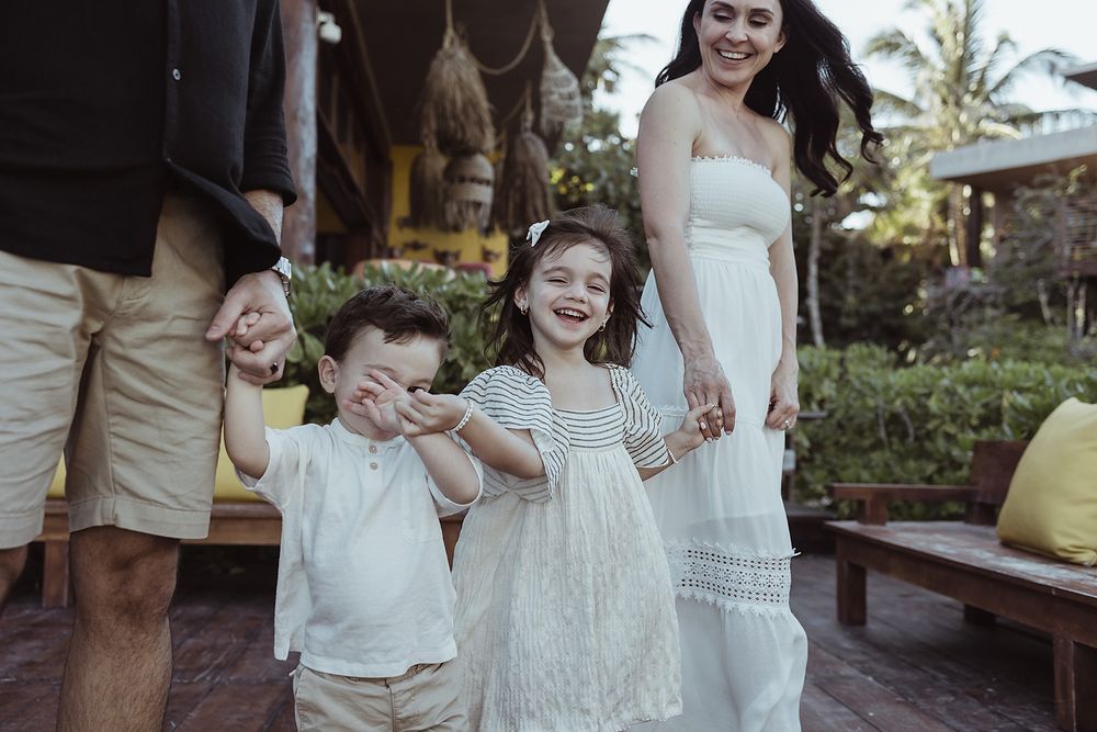 Family walking hand in hand outside La Zebra Hotel, playful vacation photoshoot in Tulum.