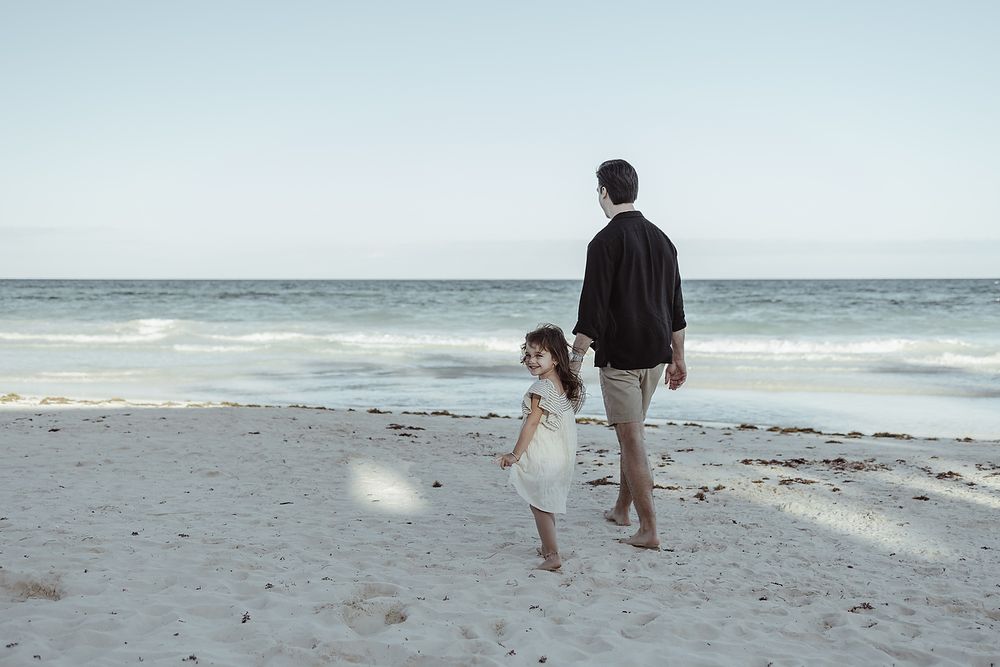 Father walking with daughter by the Caribbean Sea during family vacation photoshoot in Tulum.