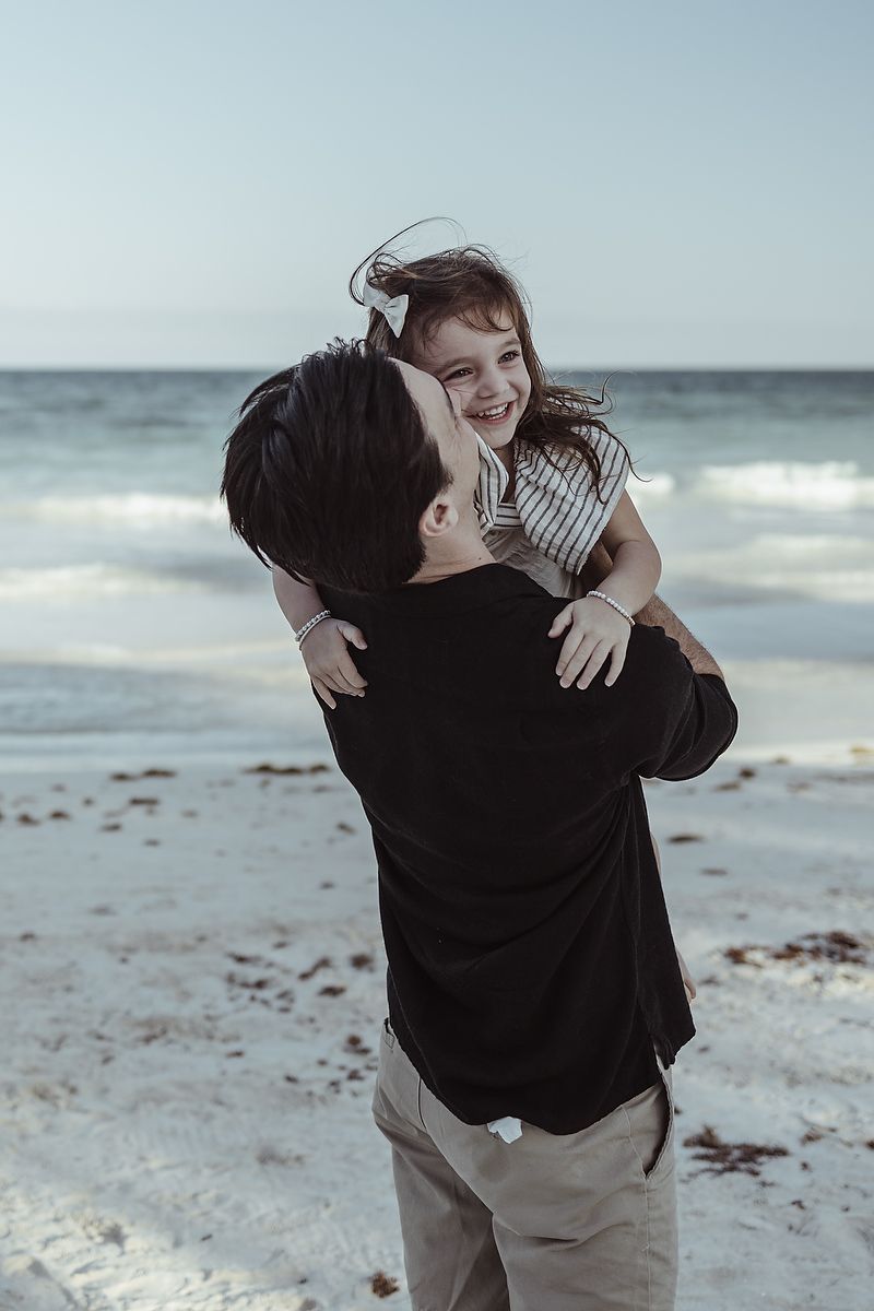 Father holding daughter by the ocean at La Zebra Hotel, playful family beach photography in Tulum.