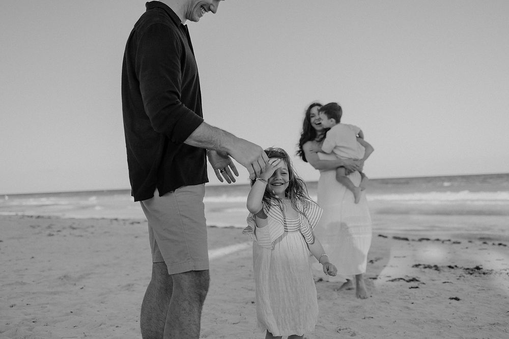 Family running and playing together on the Caribbean beach during luxury vacation photoshoot in Tulum.
