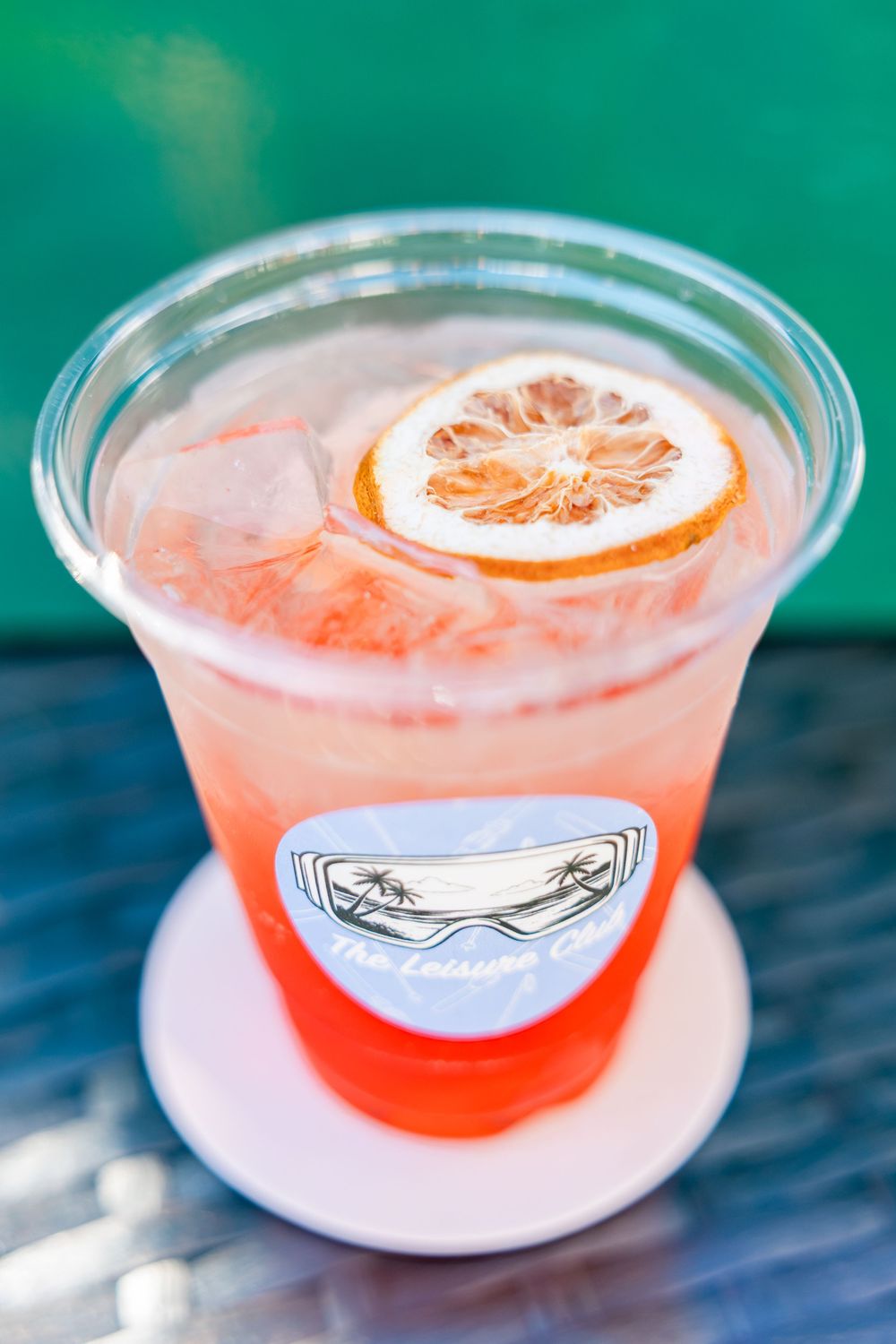 The Leisure Club branded pink cocktail with ice and dried citrus slice garnish.