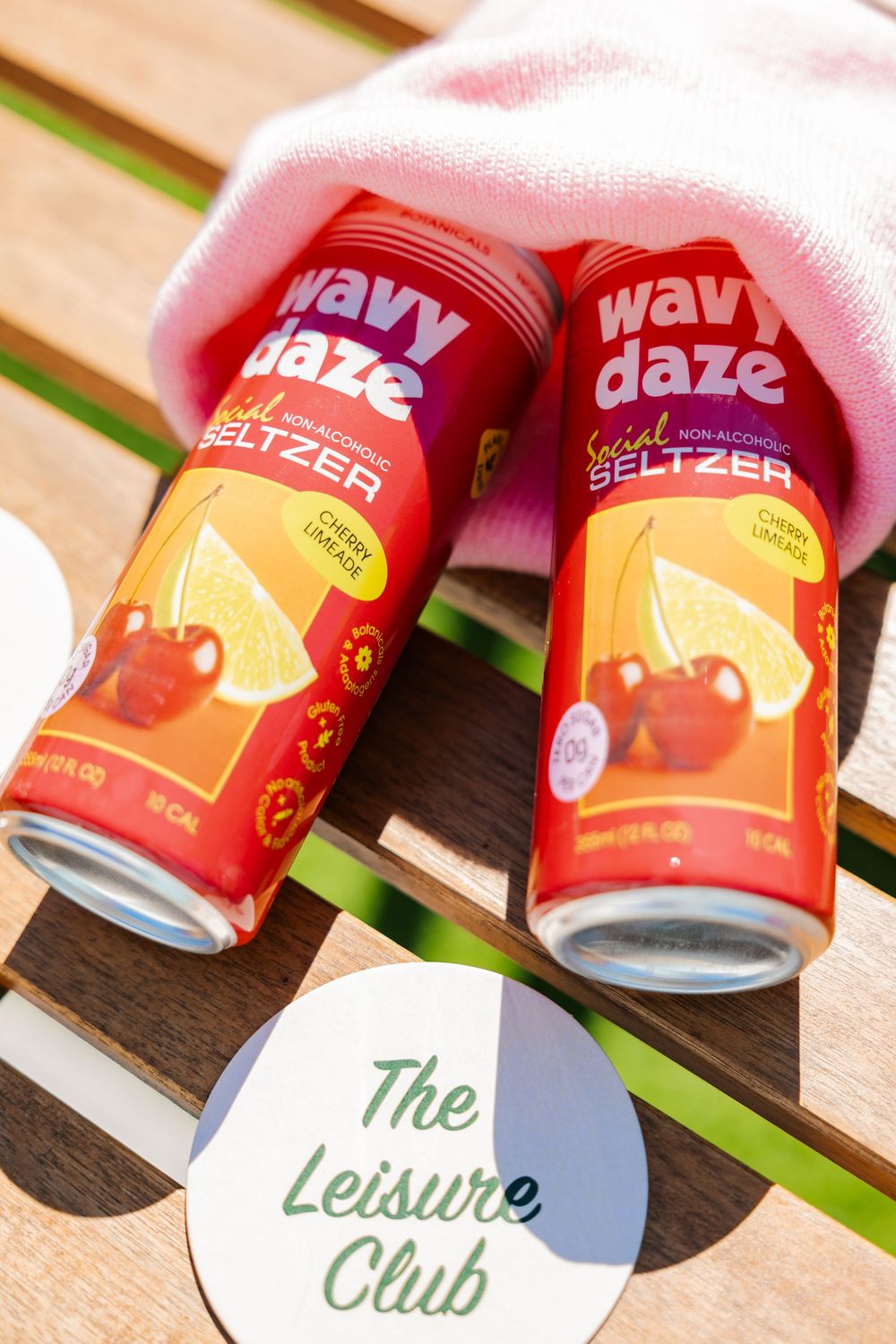 Two Wavy Daze cherry limeade non-alcoholic seltzer cans with The Leisure Club coaster.