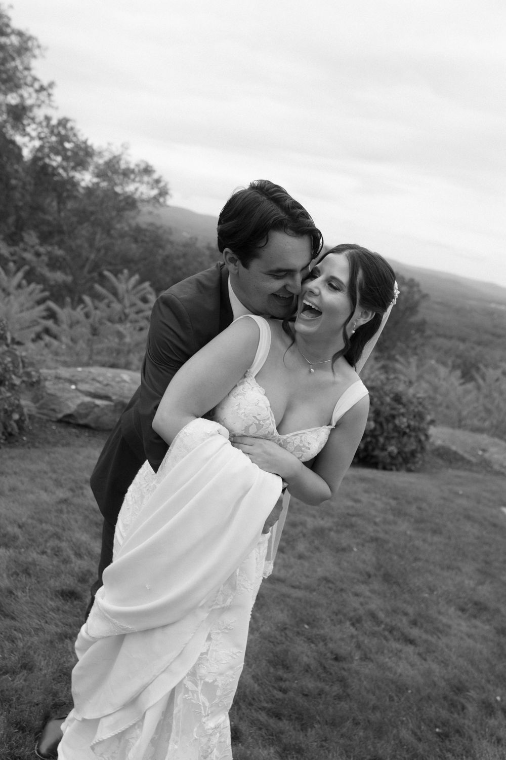 A couple shares an intimate moment together on a scenic hilltop overlooking the landscape.