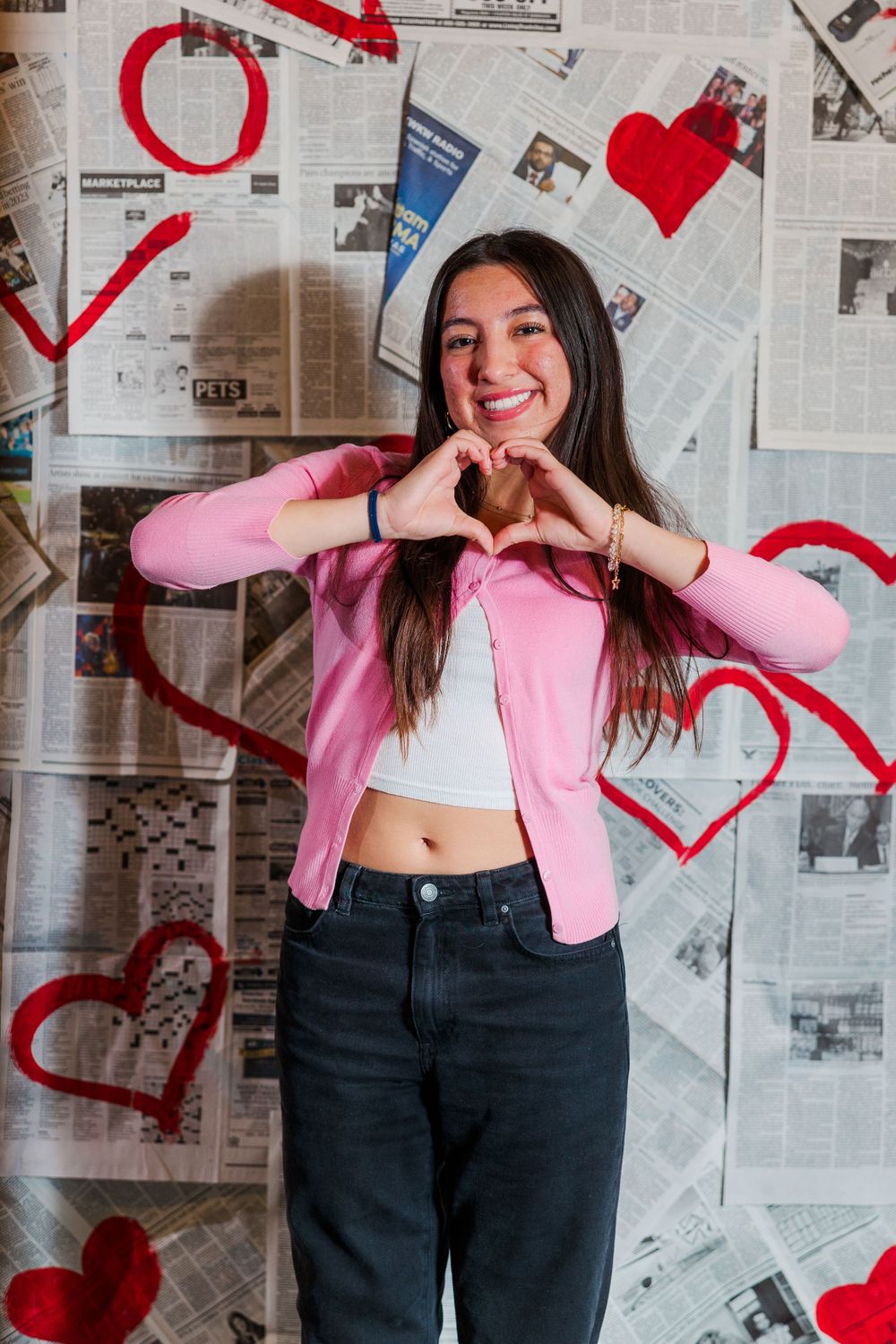 Valentine's day themed photo with paper hearts decorating newspaper background and pink clothing.