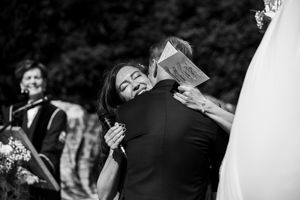 Trouwfoto van een bruidspaar, waarbij de bruid haar bruidegom emotioneel omhelst na het voorlezen van de geloftes.