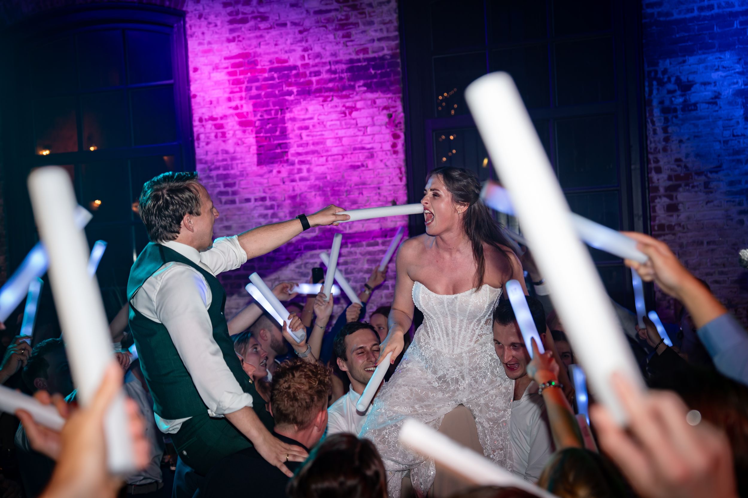 Bruidspaar gaat los tijdens hun trouwfeest. Ze zingen terwijl de bruidsgasten hun op hun schouders dragen.