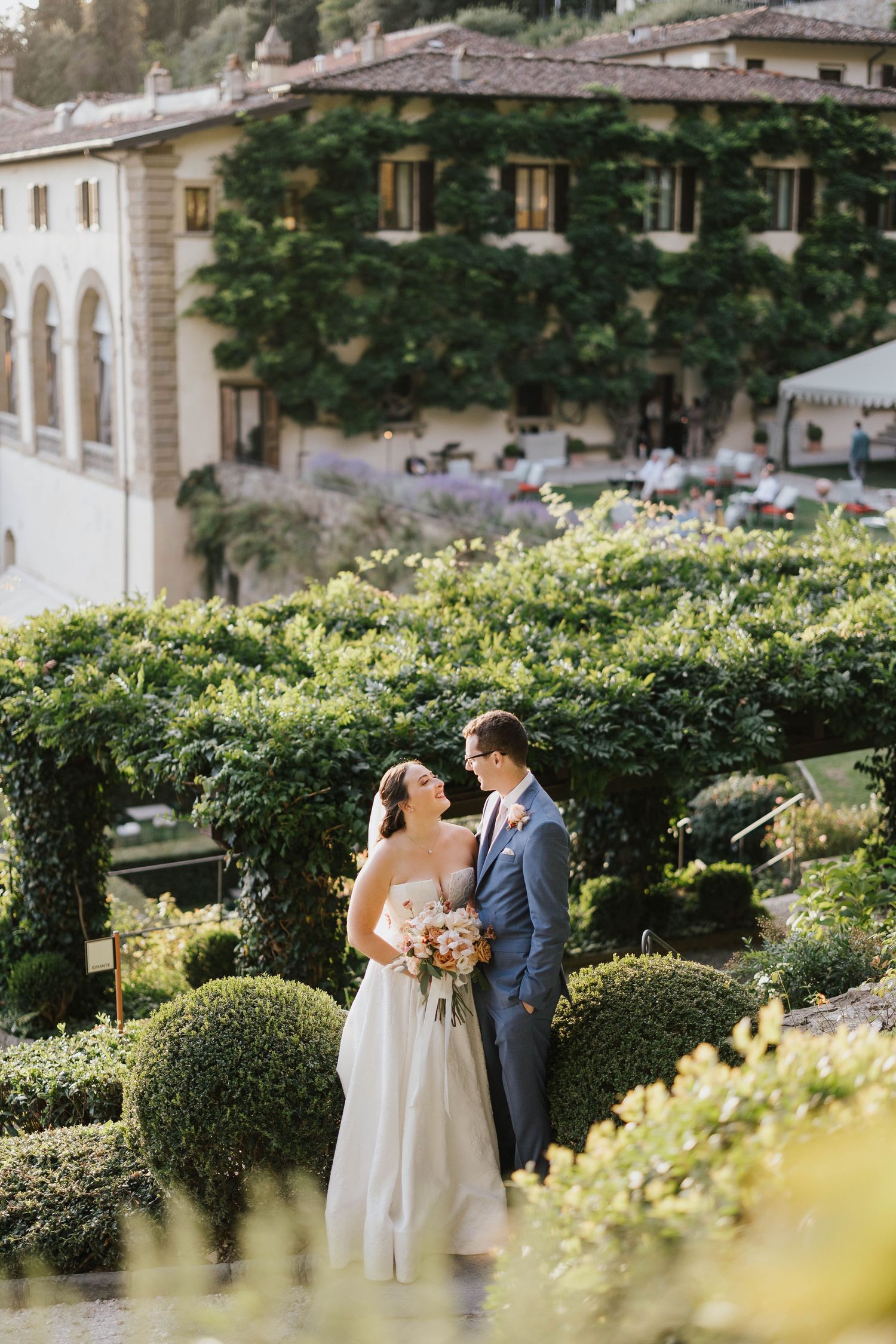 Bride and groom embracing in the gardens of Villa San Michele, Florence, surrounded by autumn light