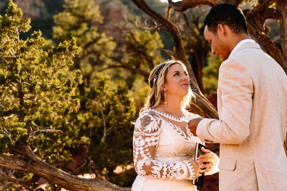 A couple shares an intimate moment during their Sedona desert wedding ceremony at sunset.