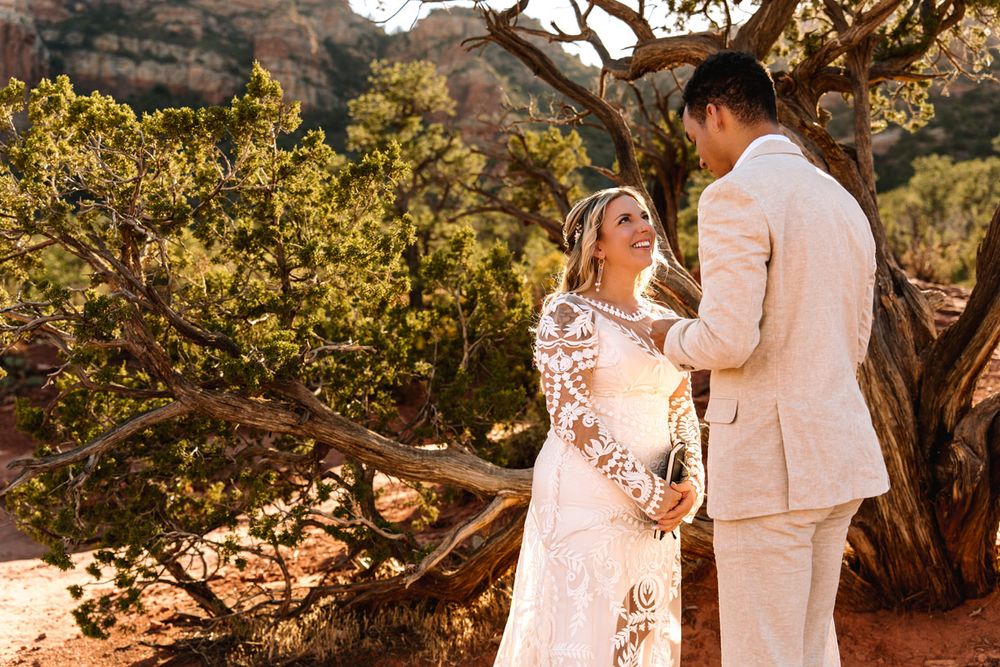 Newlyweds share romantic moment among Sedona desert landscape with golden sunlight.