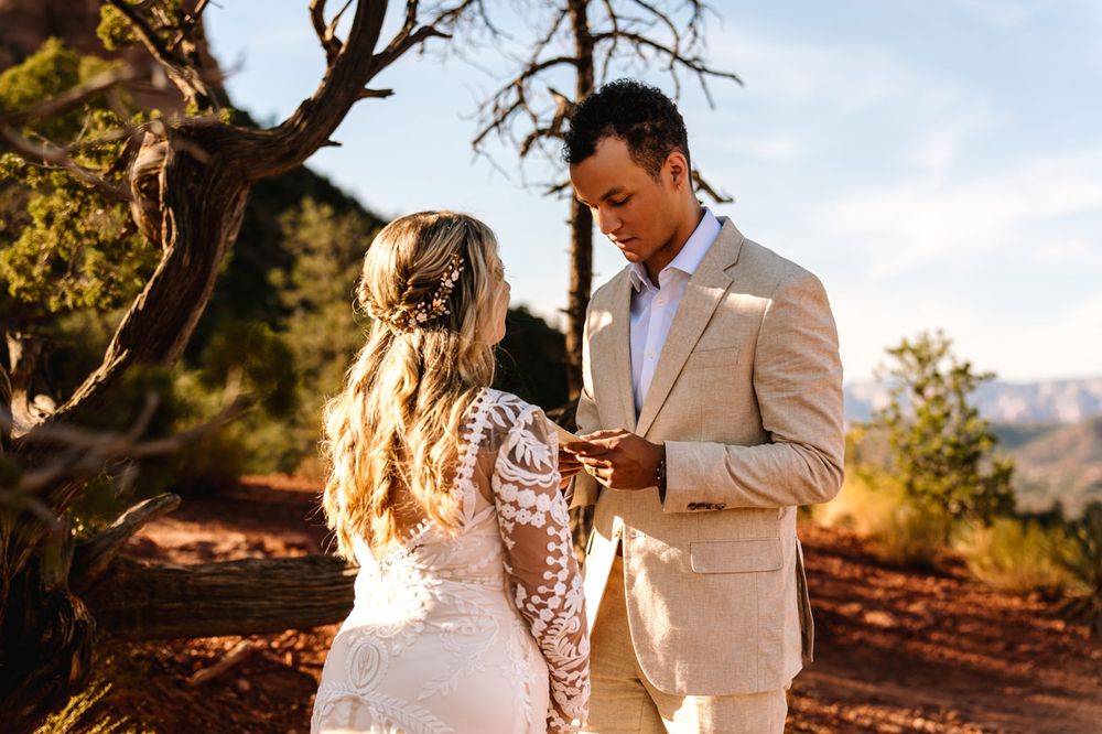 Couple in wedding attire standing together on Sedona red desert rocks.