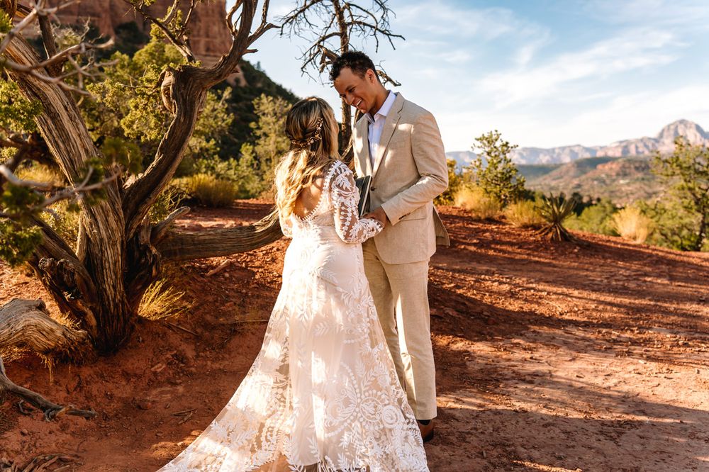 Wedding couple standing together on rustic desert trail with Sedona mountains in background.