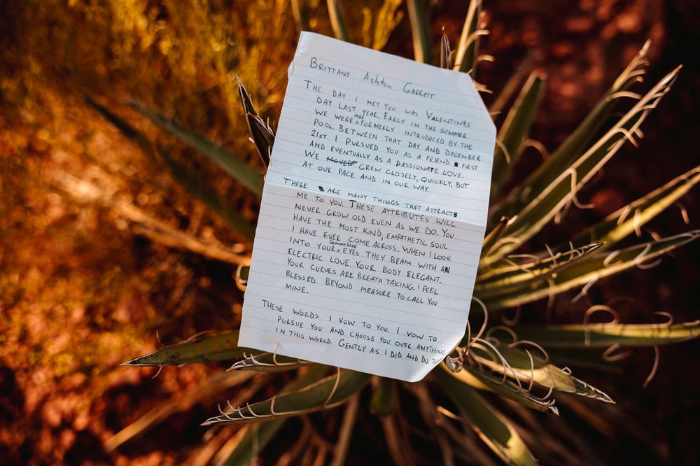 A handwritten letter or vows displayed against Sedona desert foliage with warm lighting.