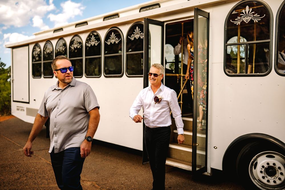 Two people exit a white wedding trolley bus parked on a Sedona desert road.