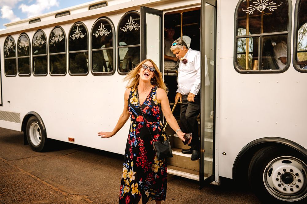 Wedding guests disembark from a white trolley bus against a Sedona desert landscape backdrop.