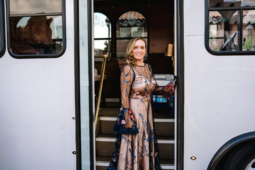 An elegant figure stands in the doorway of a white wedding trolley bus.