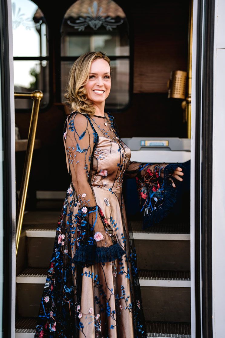 A stylish floral sheer dress with blue embroidery details being worn on a vintage trolley entrance.