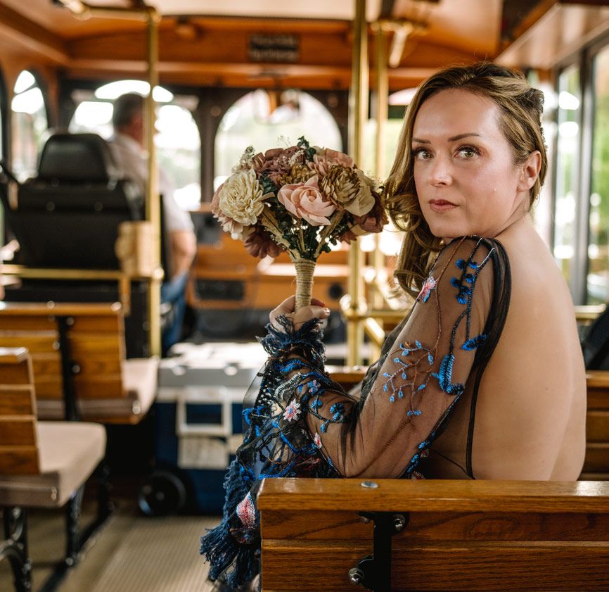 A vintage trolley interior with wooden benches and decorative floral arrangements.