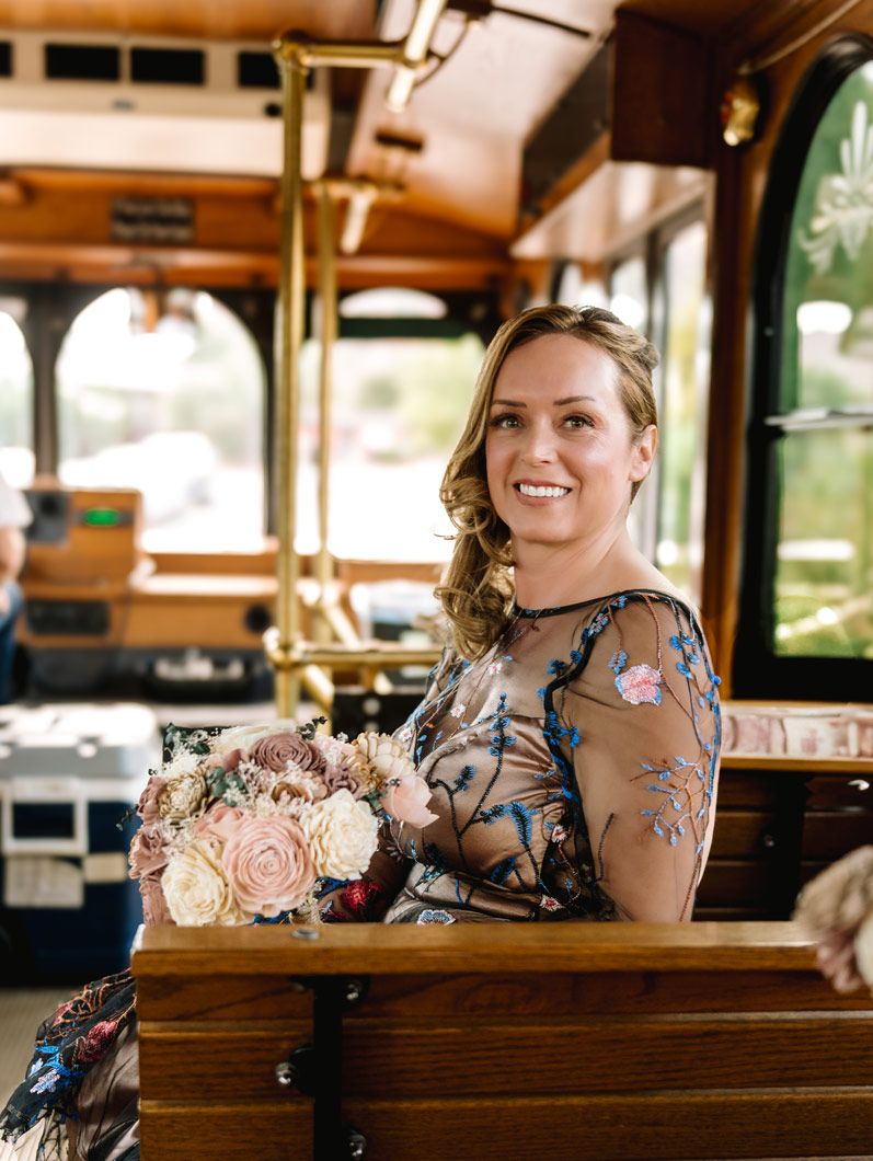 A wedding party member holding a pink and cream bouquet inside a historic trolley car.