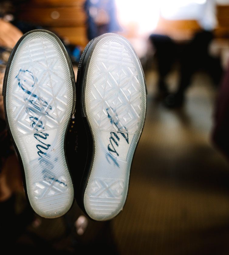Wedding shoe soles with special messages written in blue script on clear bottoms.