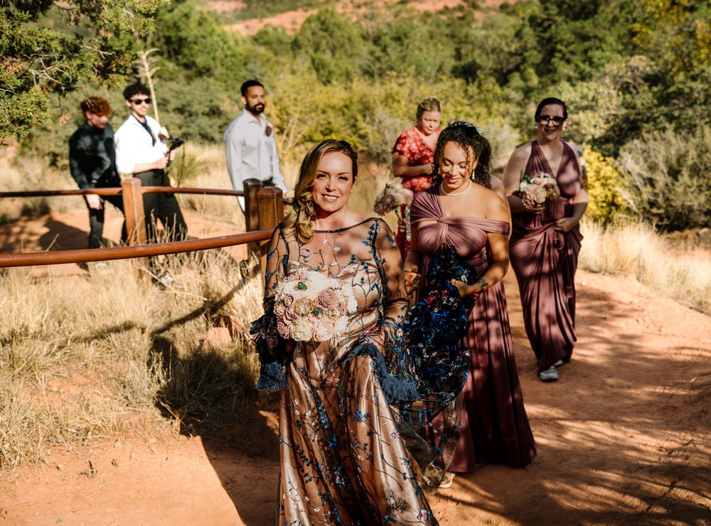 Wedding party members walking along a Sedona desert trail with mountain scenery in the background.