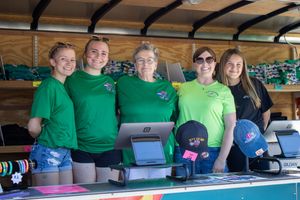 Volunteers in green shirts staff a concession booth at an outdoor event.