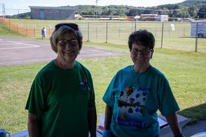 Volunteers in green and blue shirts serving at an outdoor community gathering.