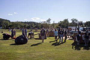 Crowd gathered on grassy field for outdoor community event under blue skies.