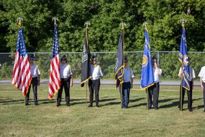 Color guard members standing in formation with flags during outdoor ceremony.