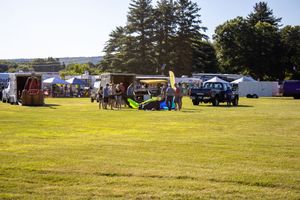 Panoramic view of a hot air balloon festival field with attendees and equipment scattered across the grounds.