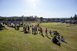 Wide panoramic view of a balloon festival field with crowds spread across the landscape.