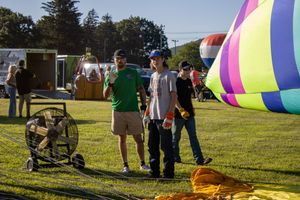 Spectators gathering around colorful hot air balloons during an outdoor festival setup.