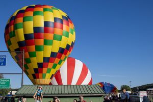 Colorful hot air balloons with geometric patterns displayed against clear blue skies.