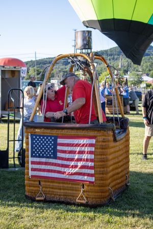 Wicker balloon baskets decorated with American flags displayed on grass at a festival.