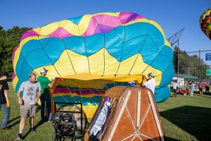 Vibrant rainbow-colored hot air balloon envelope being inflated on the ground.