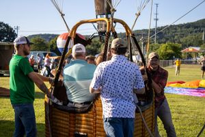 Crew members work together to prepare a hot air balloon basket for flight.
