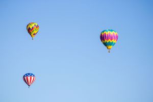 Colorful hot air balloons floating against a bright blue sky during a festival.