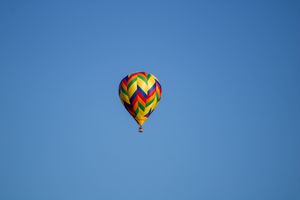 Geometric patterned hot air balloons floating in a cloudless sky.
