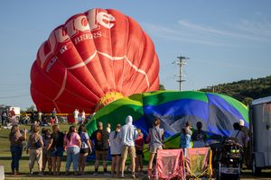Red hot air balloon being inflated on the ground during setup.