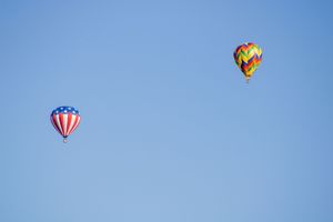 Hot air balloons with American flag designs floating in blue skies.