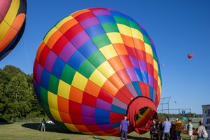Colorful patchwork hot air balloons display their vibrant patterns against a clear blue sky.