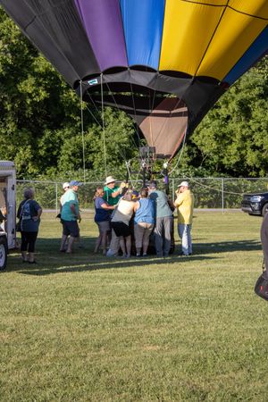 A striped hot air balloon envelope draws a crowd of onlookers at a festival.