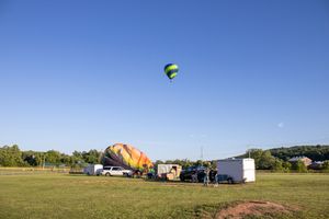 Hot air balloons and support vehicles scattered across an open field during a balloon event.