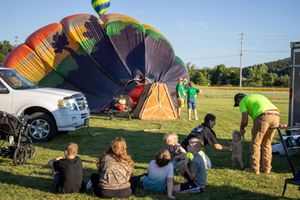 Ground crew working together to prepare colorful hot air balloons for launch.
