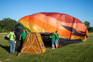 Deflated hot air balloons laid out on grass being prepared for inflation.